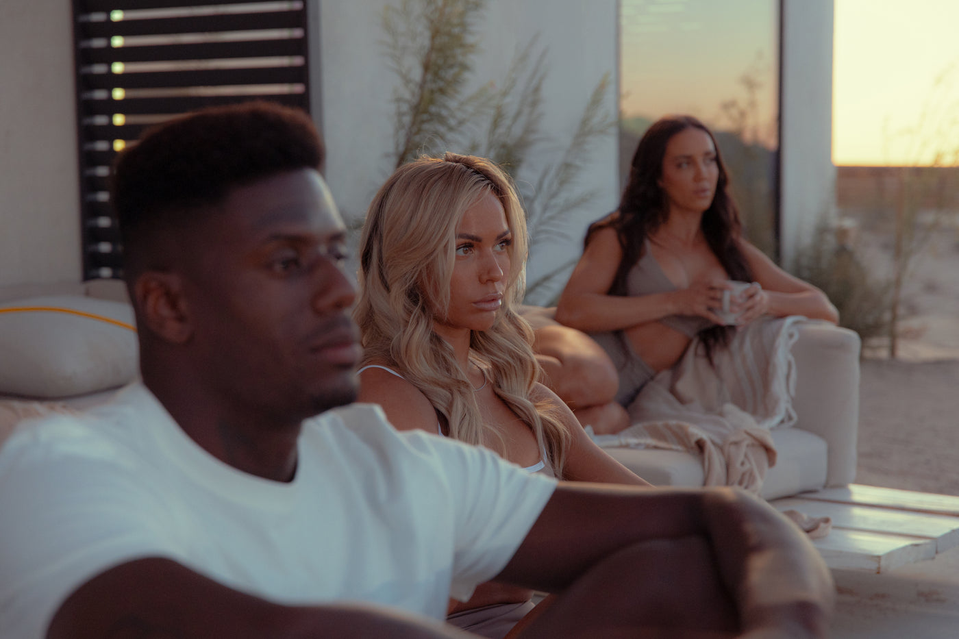 Three people relaxing together outdoors at sunset in a desert setting